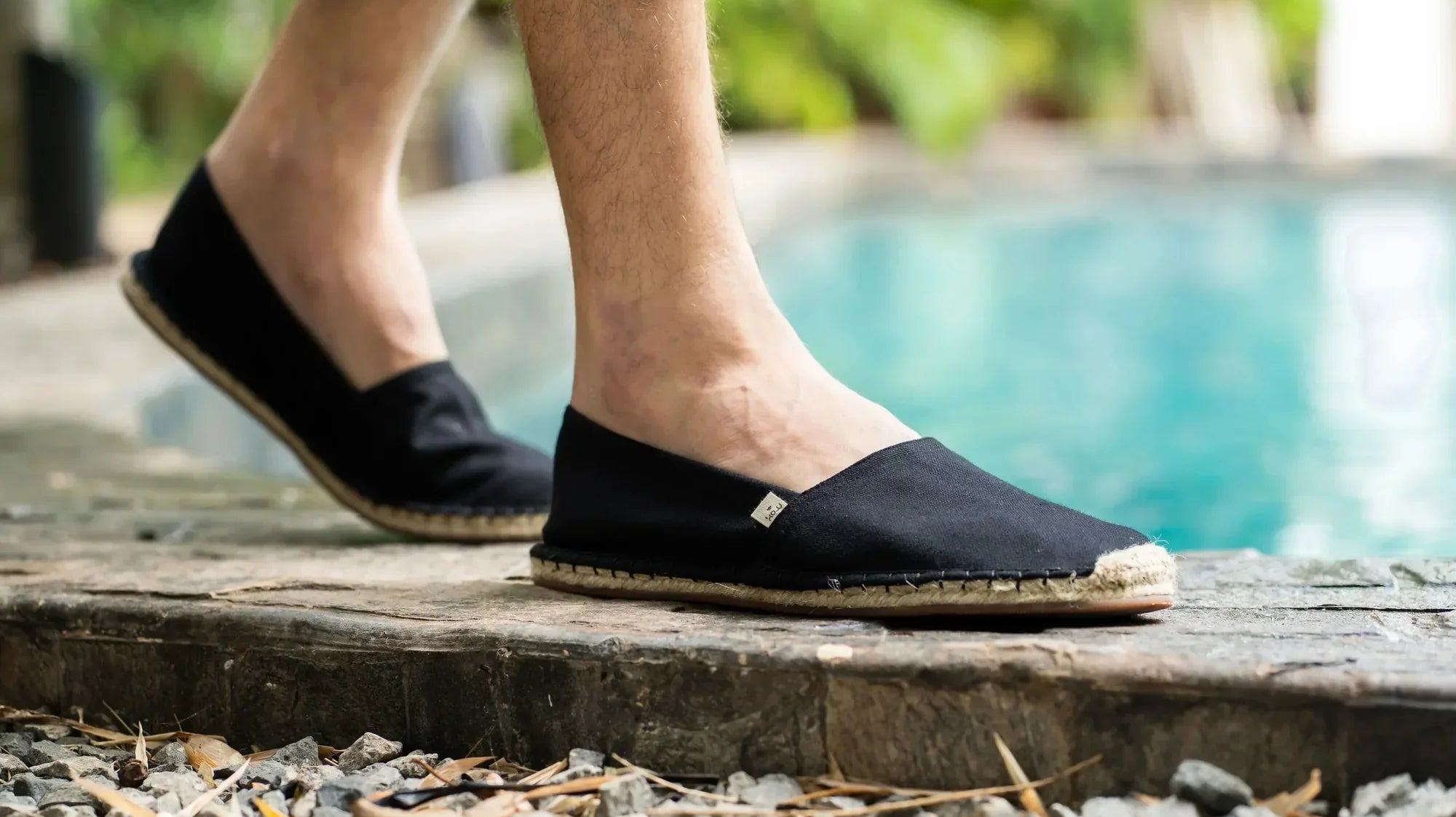 man walking around swimming pool in black espadrilles