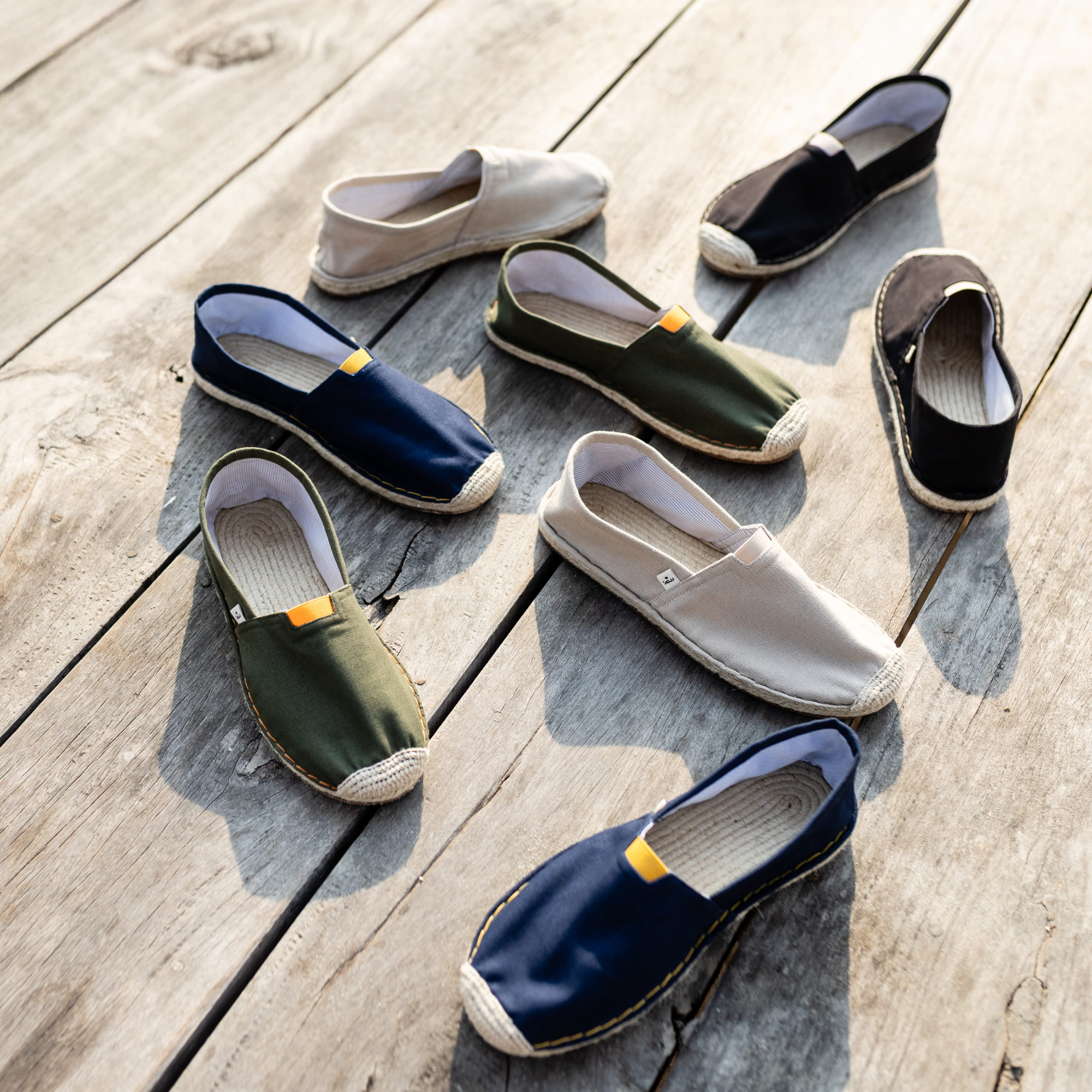 Collection of casual espadrille shoes in various colors on a wooden surface