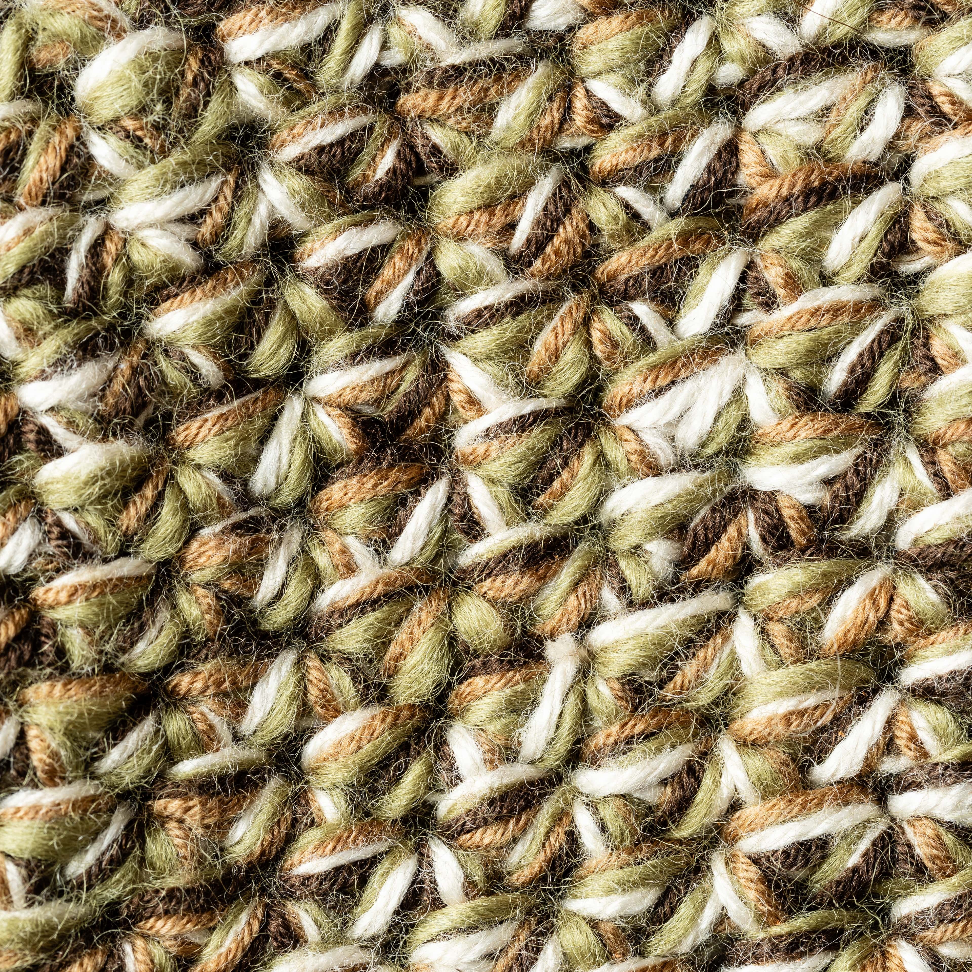 Close-up of a textured fabric with a wicker pattern in green, brown, and white.