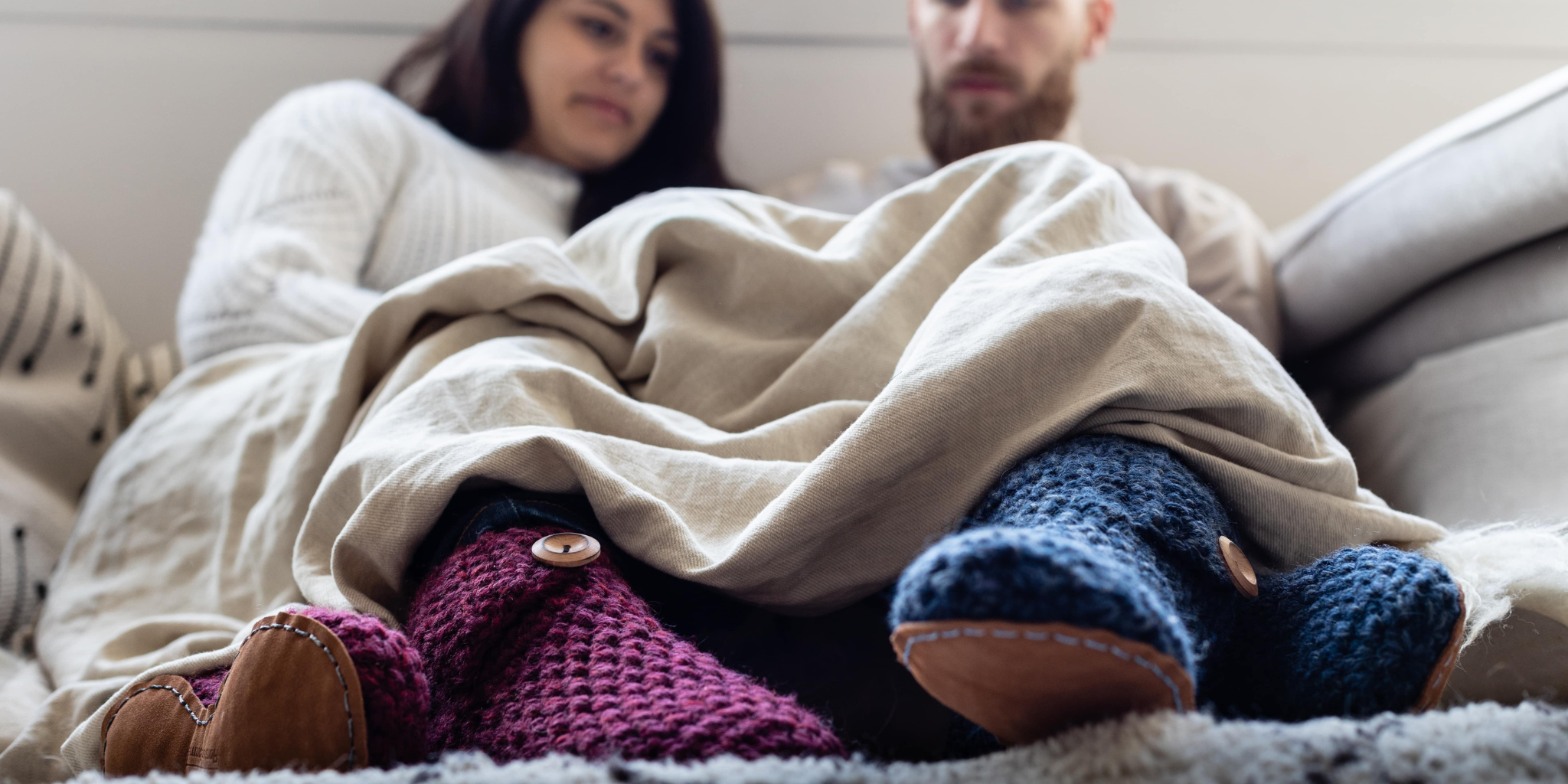 Couple under a blanket wearing wool slippers