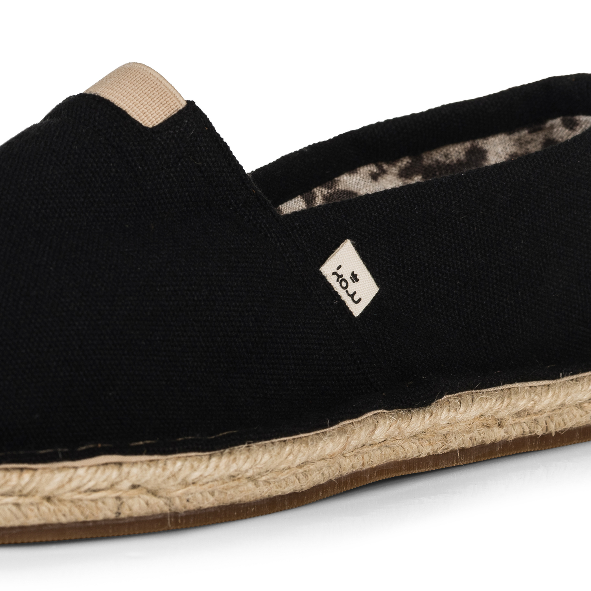 Close up of a black espadrille shoe with jute rope sole on a white background