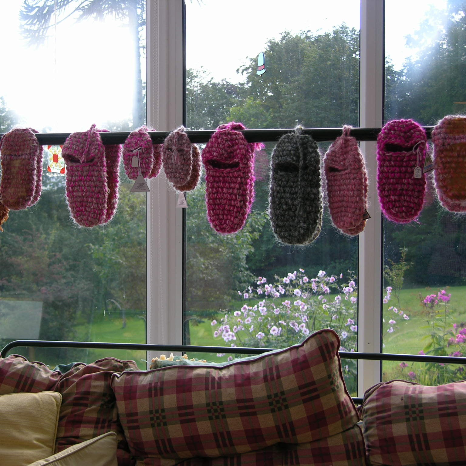 Old styles of colorful crocheted slippers hanging over a rail