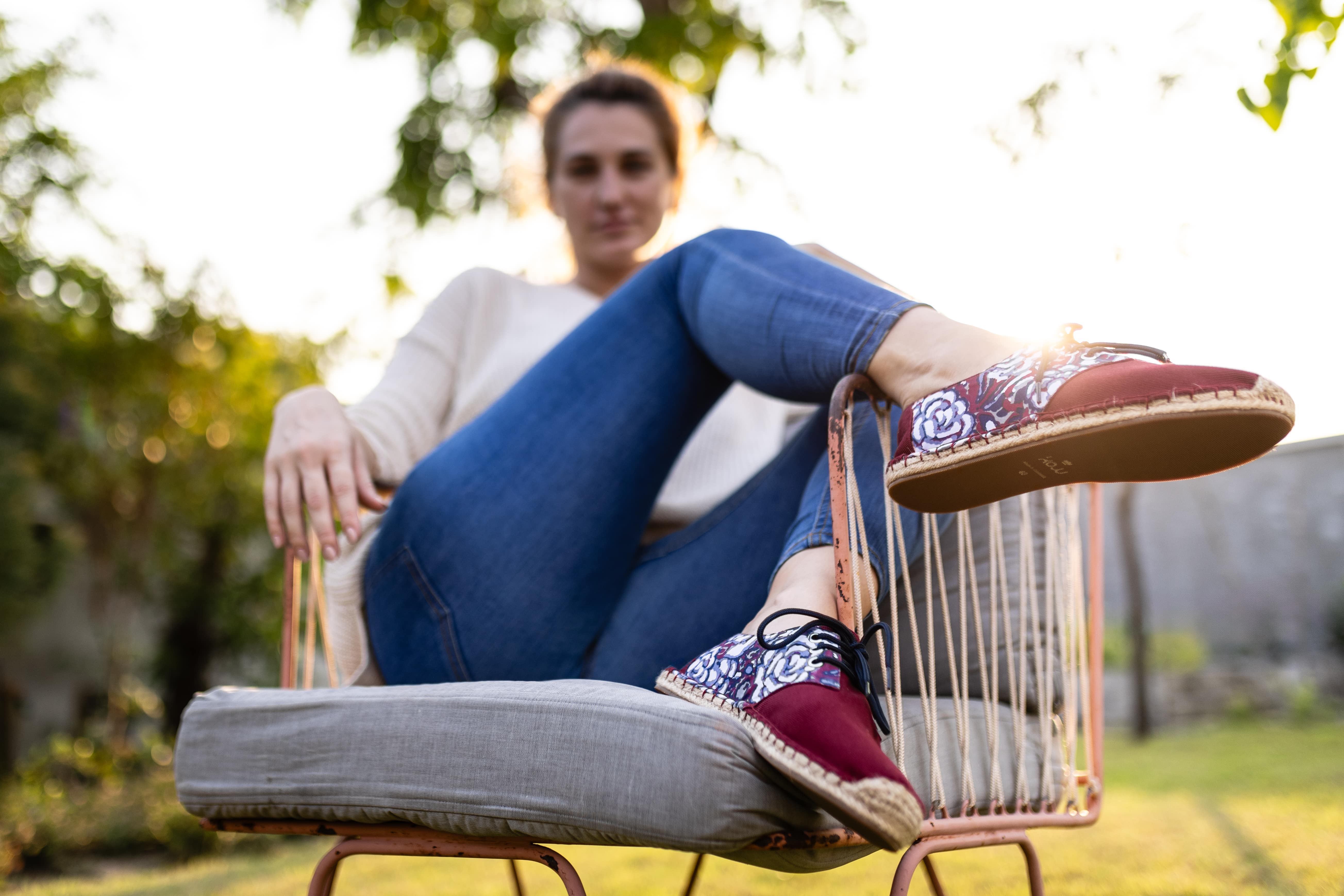 Woman sits in chair wearing Kingdom of Wow's Red Lace up Espadrilles