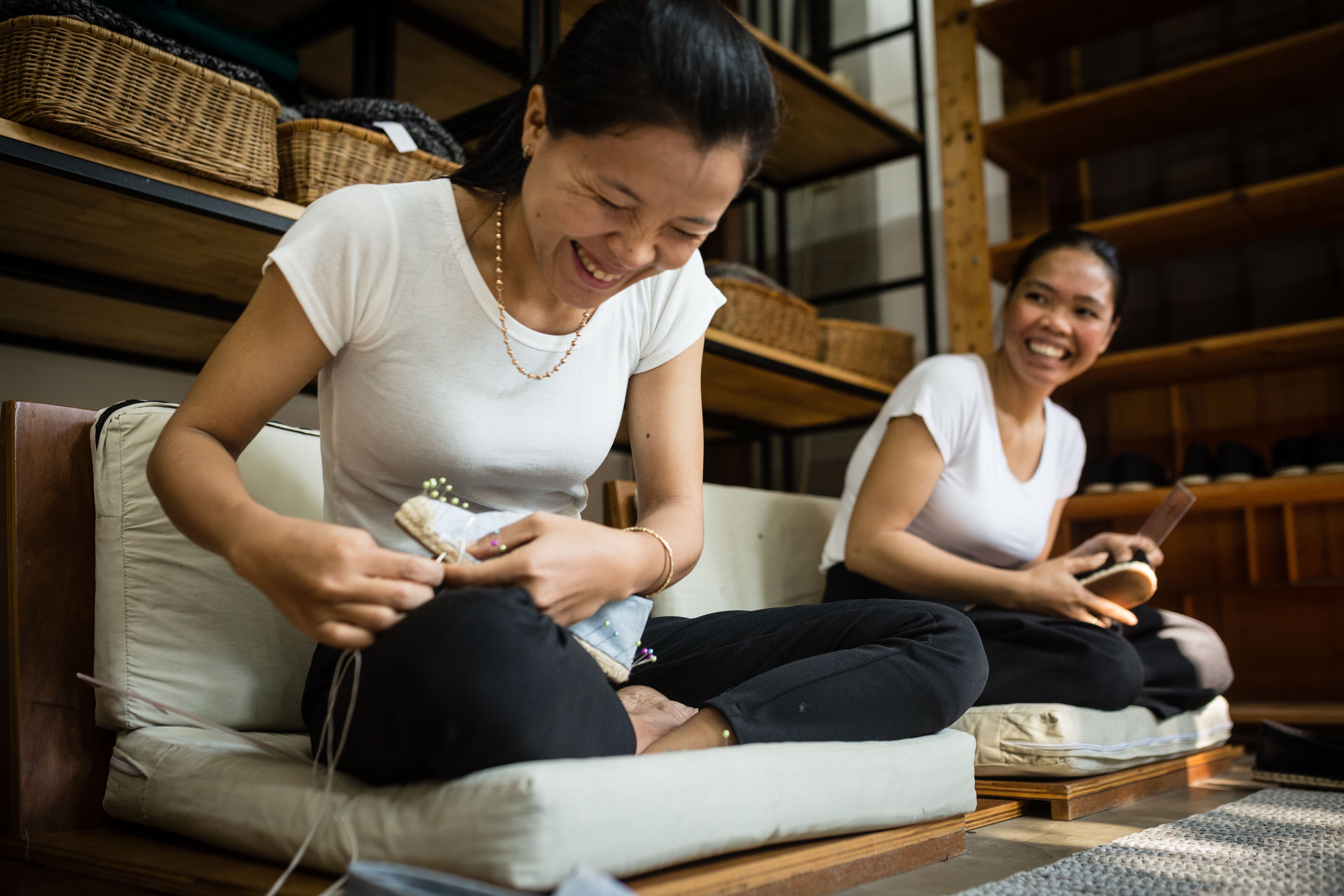 Two artisans in jovial discussion whilst crafting espadrilles