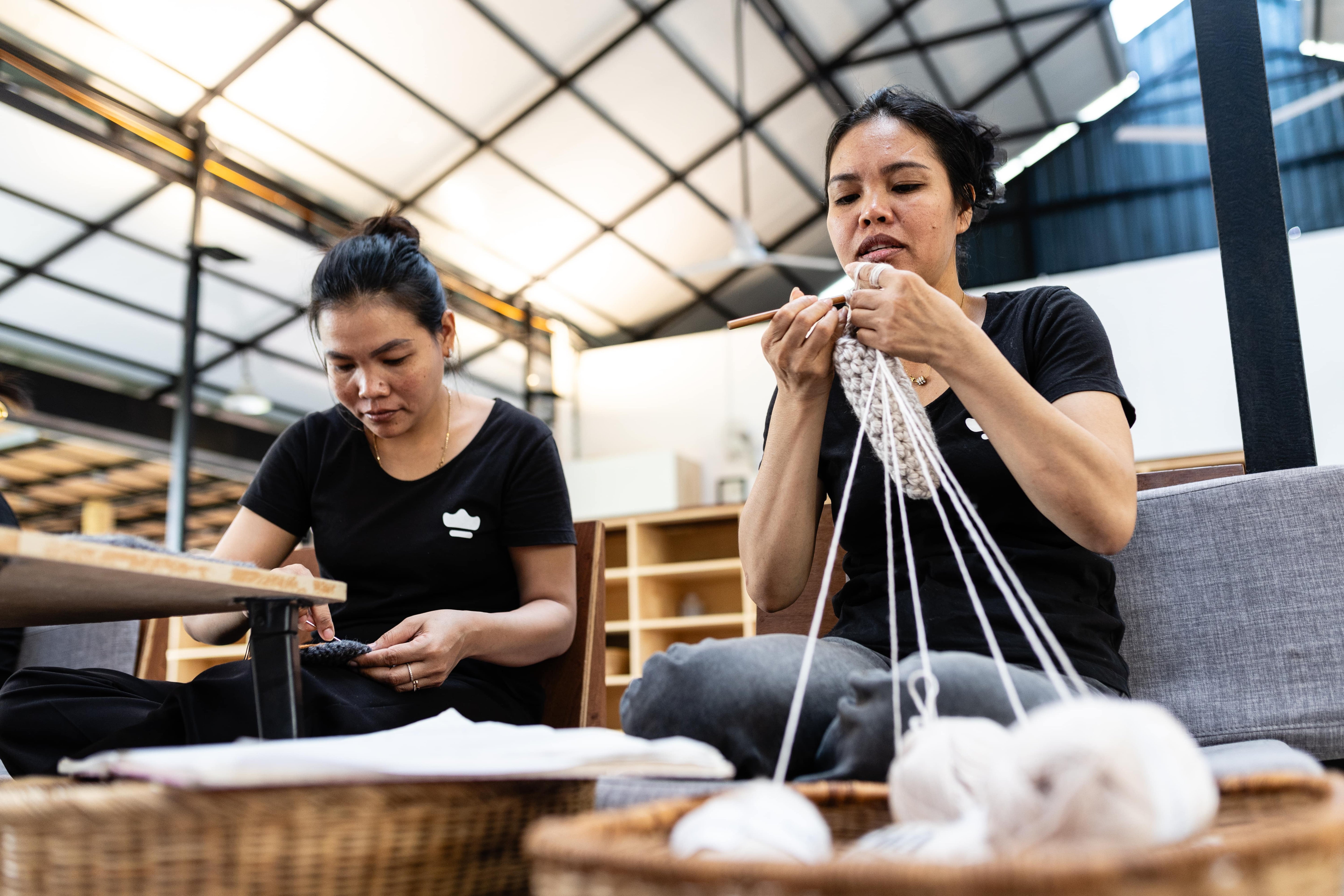 Two female artisans in the workshop crocheting wool slippers