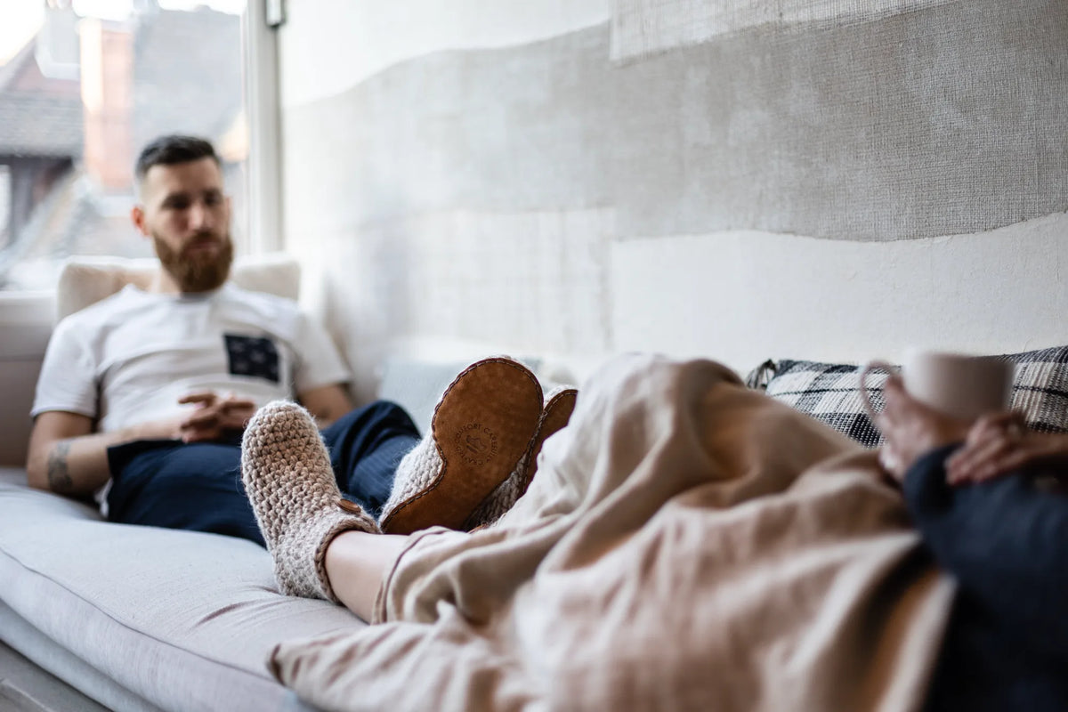 Couple relaxing on a sofa wearing cozy wool slippers by KOW