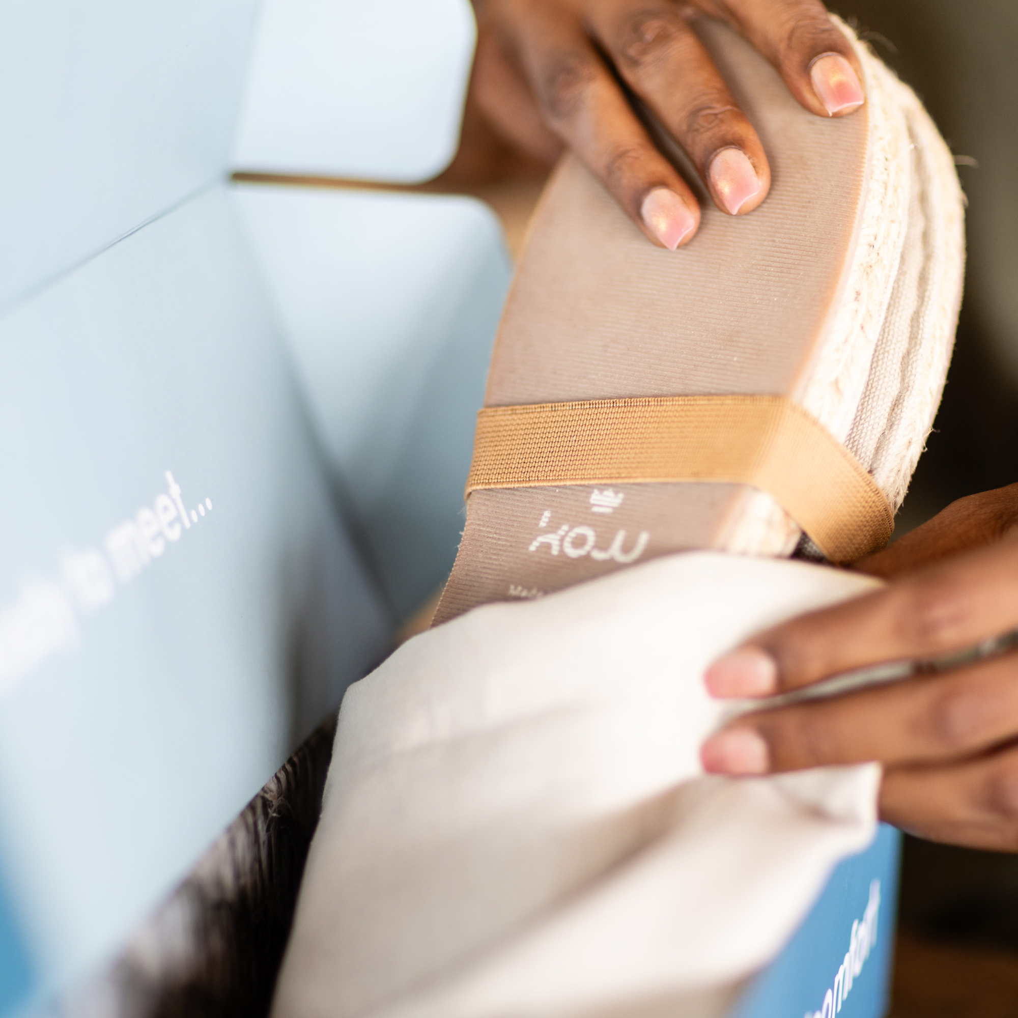 Person unpacking a pair of espadrille shoes with KOW branding
