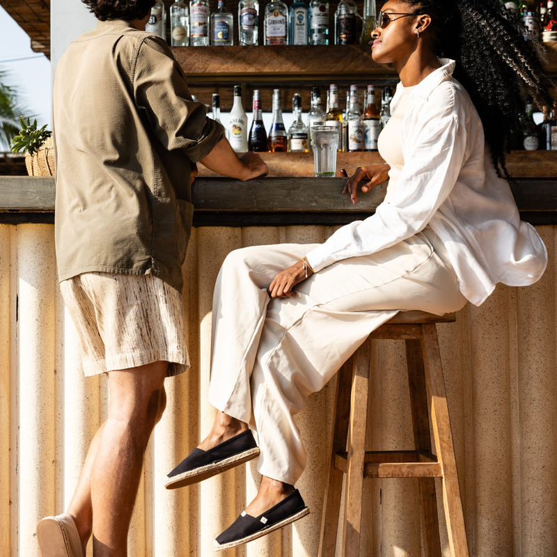 Two people at a bar with drinks and bottles in the background