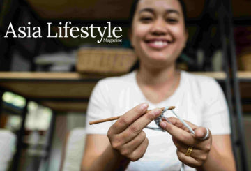 Woman holding crochet hooks with a blurred background and 'Asia Lifestyle' magazine text.