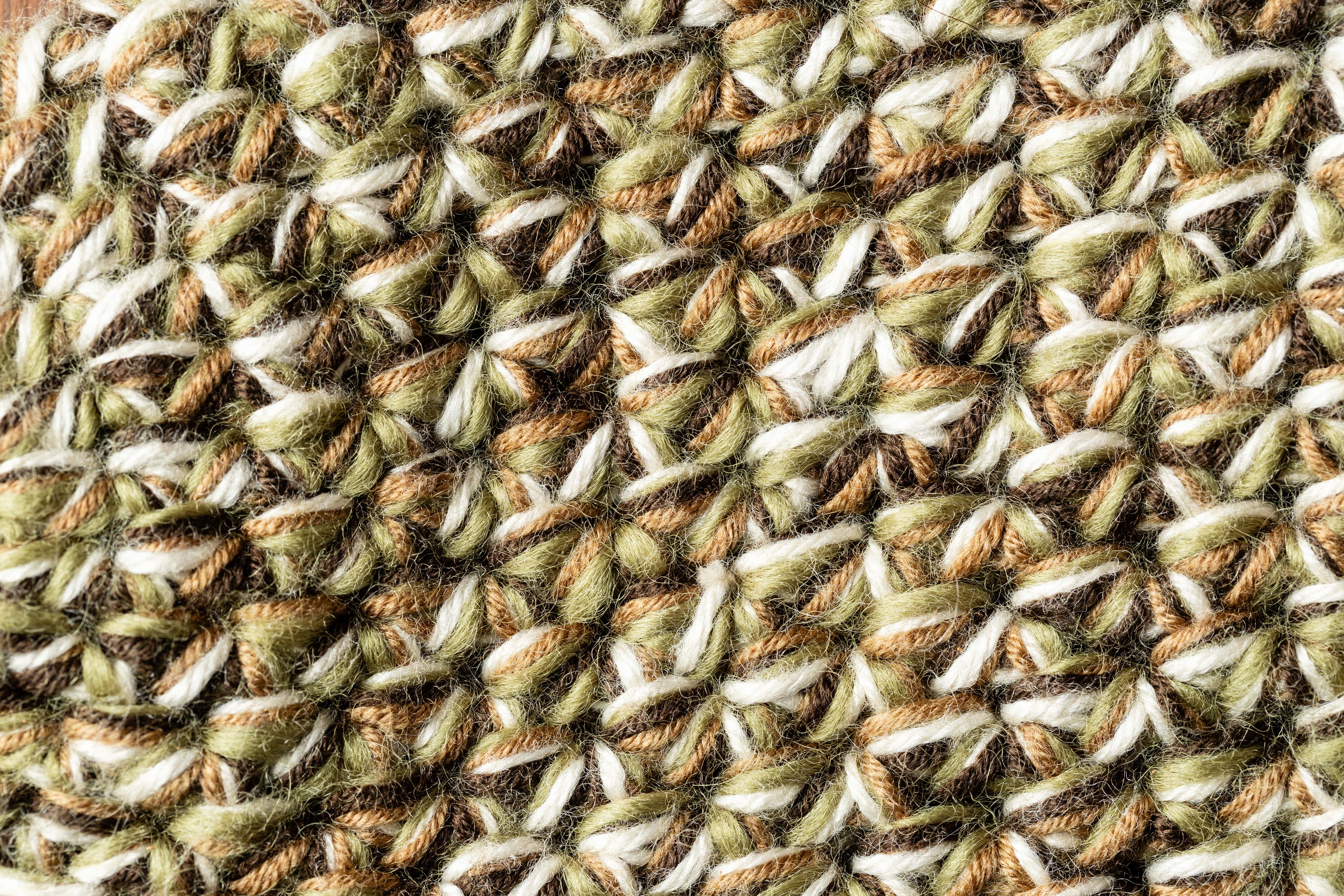 Close-up of a textured fabric with a wicker pattern in green, brown, and white.