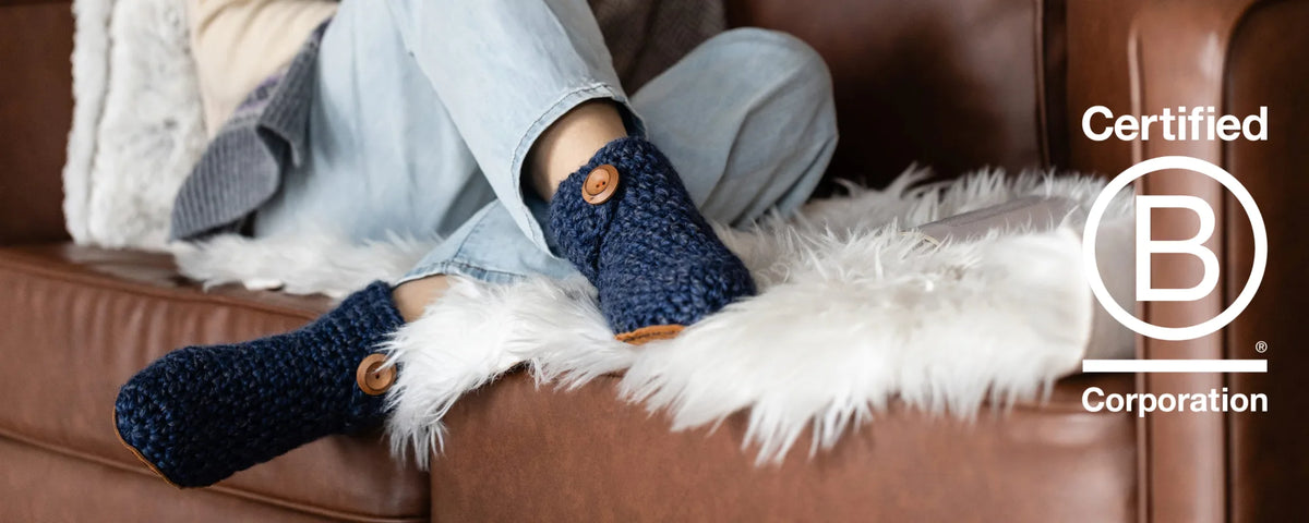 Woman sitting on couch wearing navy blue wool boot slippers