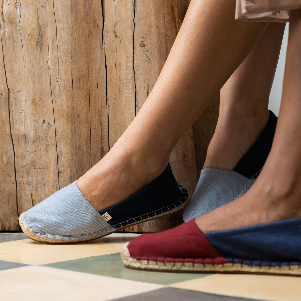 Close-up of feet wearing colorful espadrilles on a checkered floor with wooden wall background