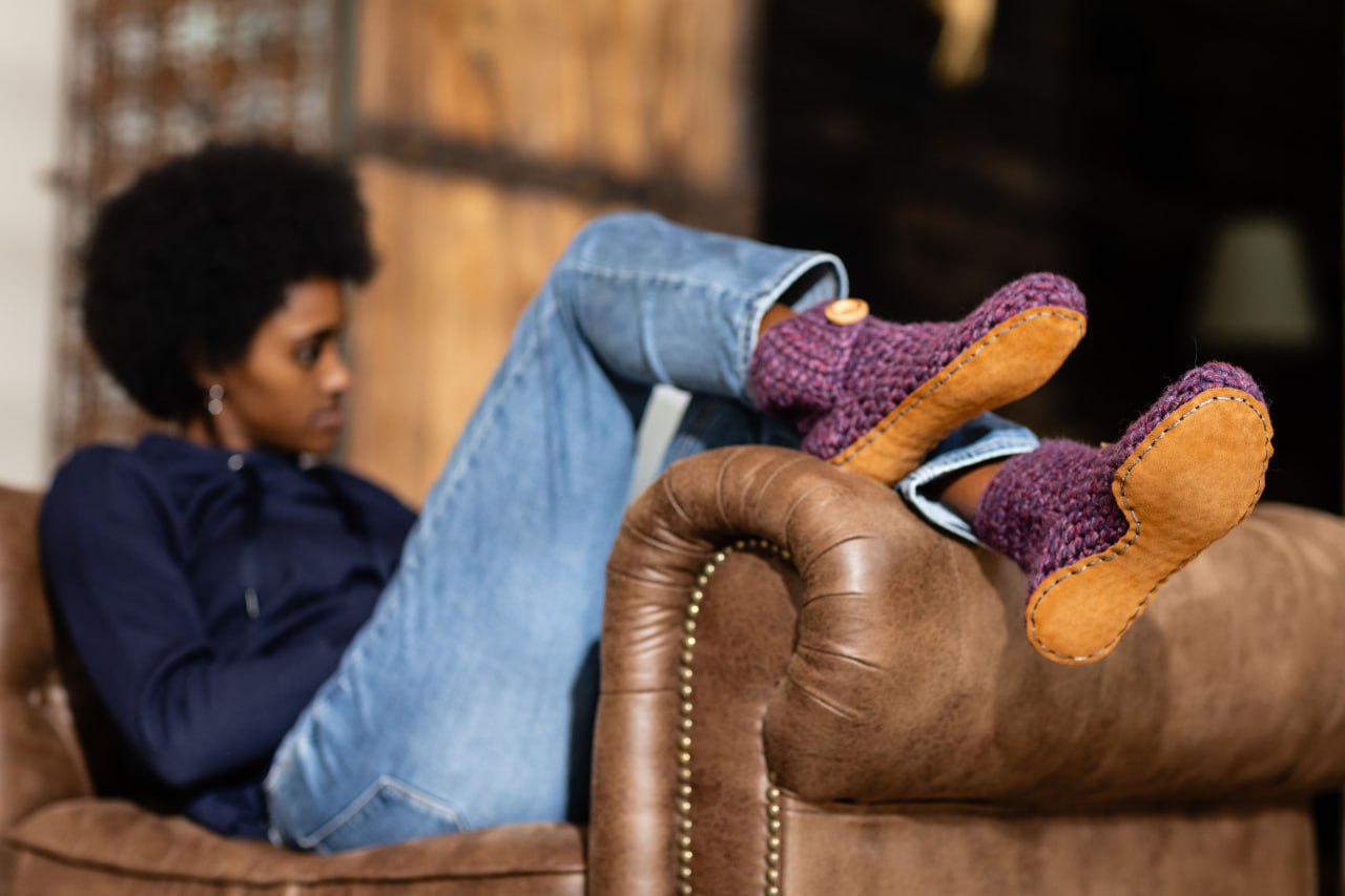 Woman wearing purple slippers relaxing on leather armchair