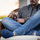 Person sitting on a couch with a dog in their lap, wearing blue wool slippers.