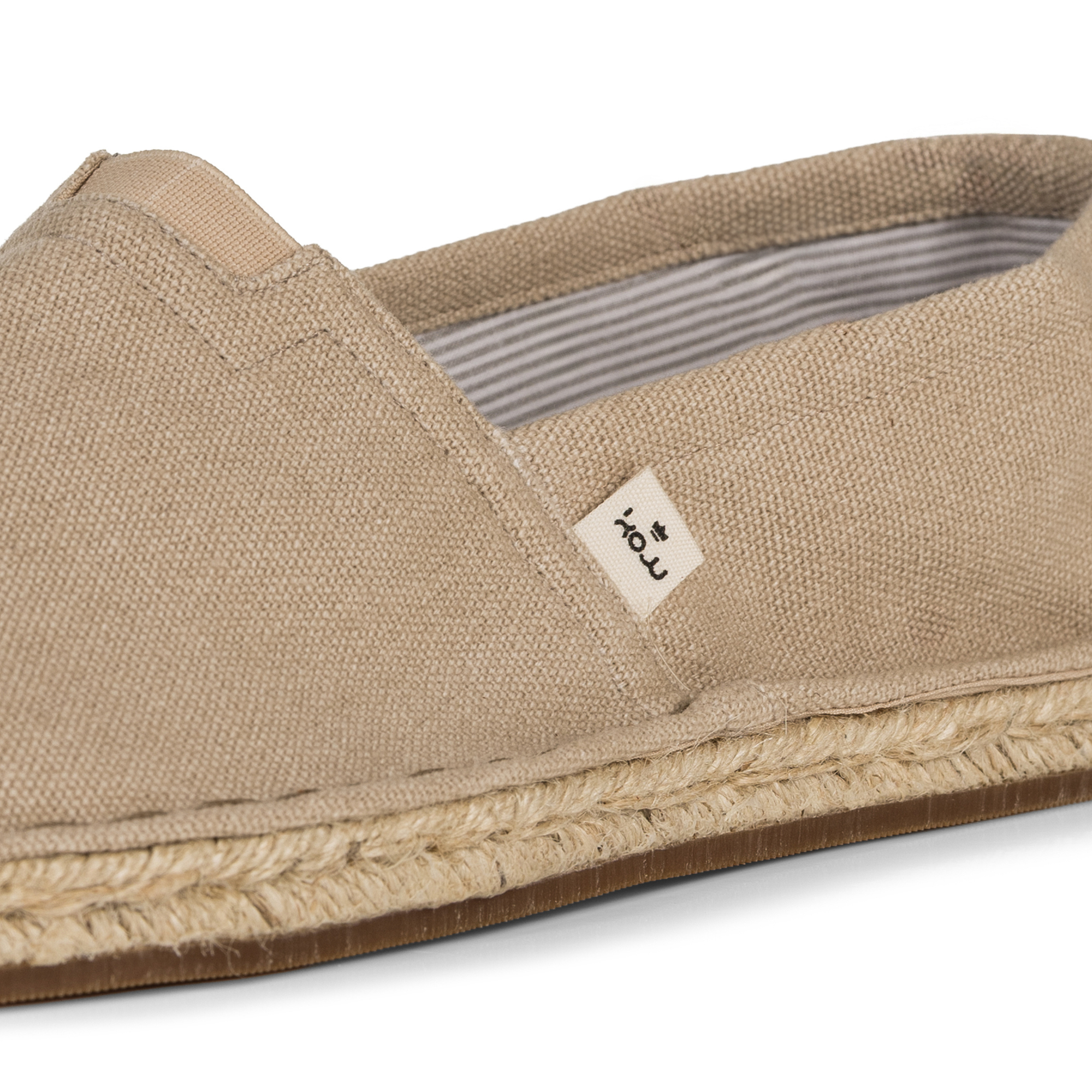 Clsoe up of beige espadrille shoe with KOW brand label on a white background
