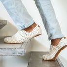 Person climbing stairs wearing white crocheted house shoes worn with light blue jeans