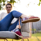 Woman wearing red lace-up espadrilles with floral patterns sitting outdoors.