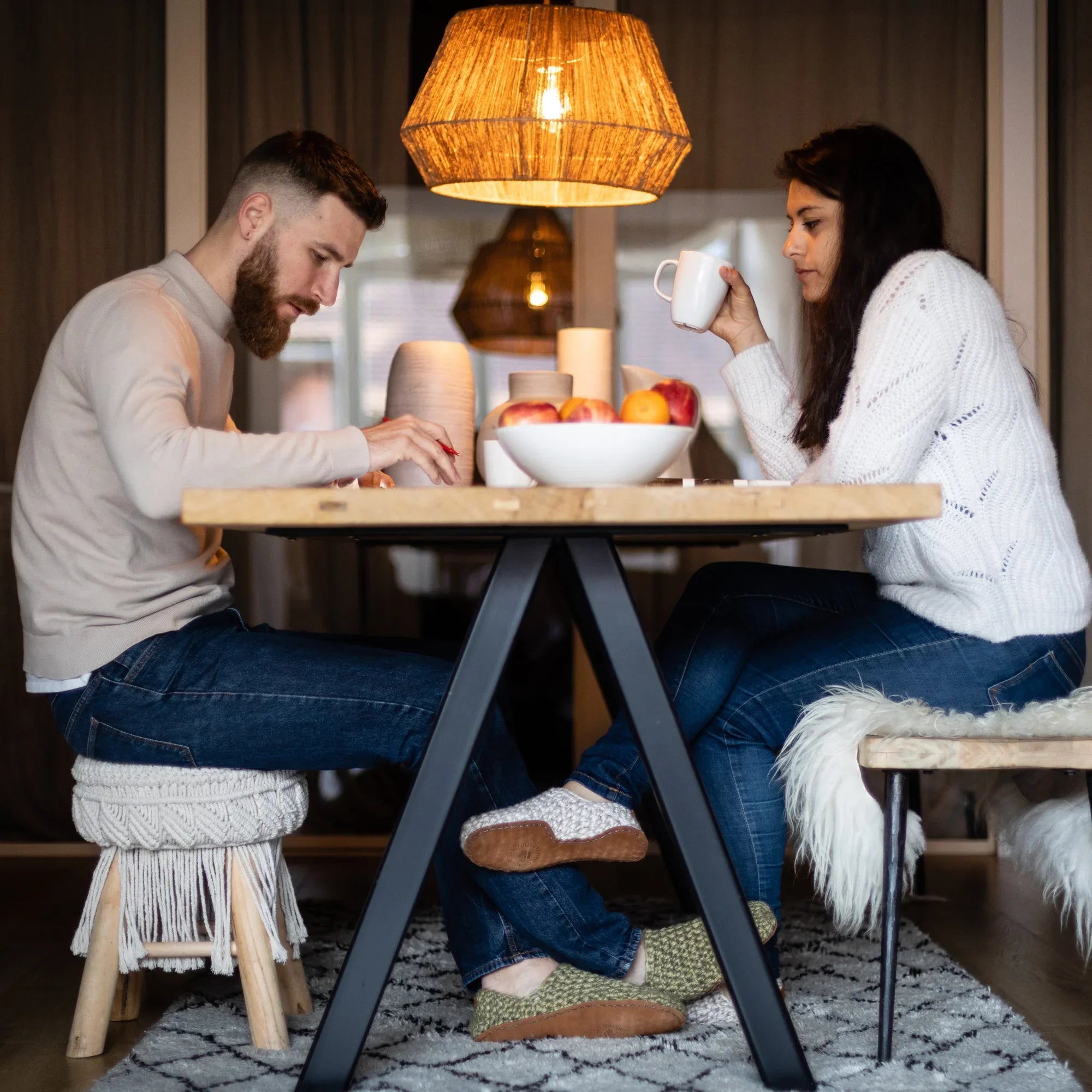 Man and woman sitting relaxing at a table in a cozy room wearing wool slippers.