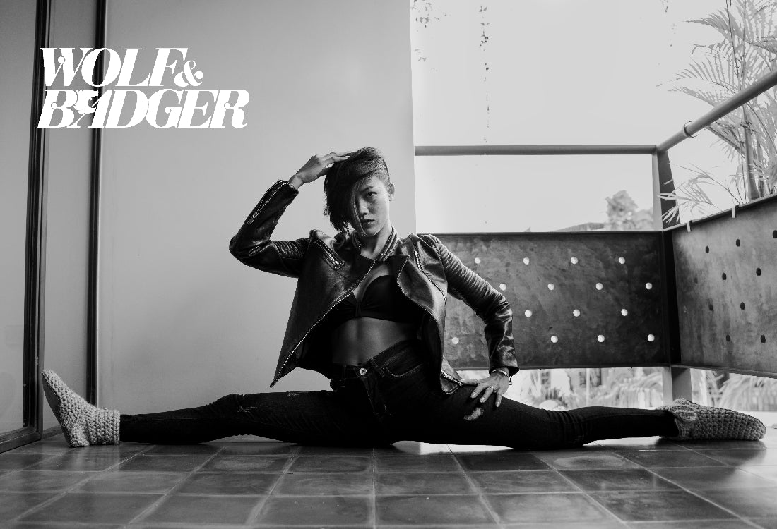 Person in a split pose wearing a leather jacket with 'Wolf & Badger' branding.