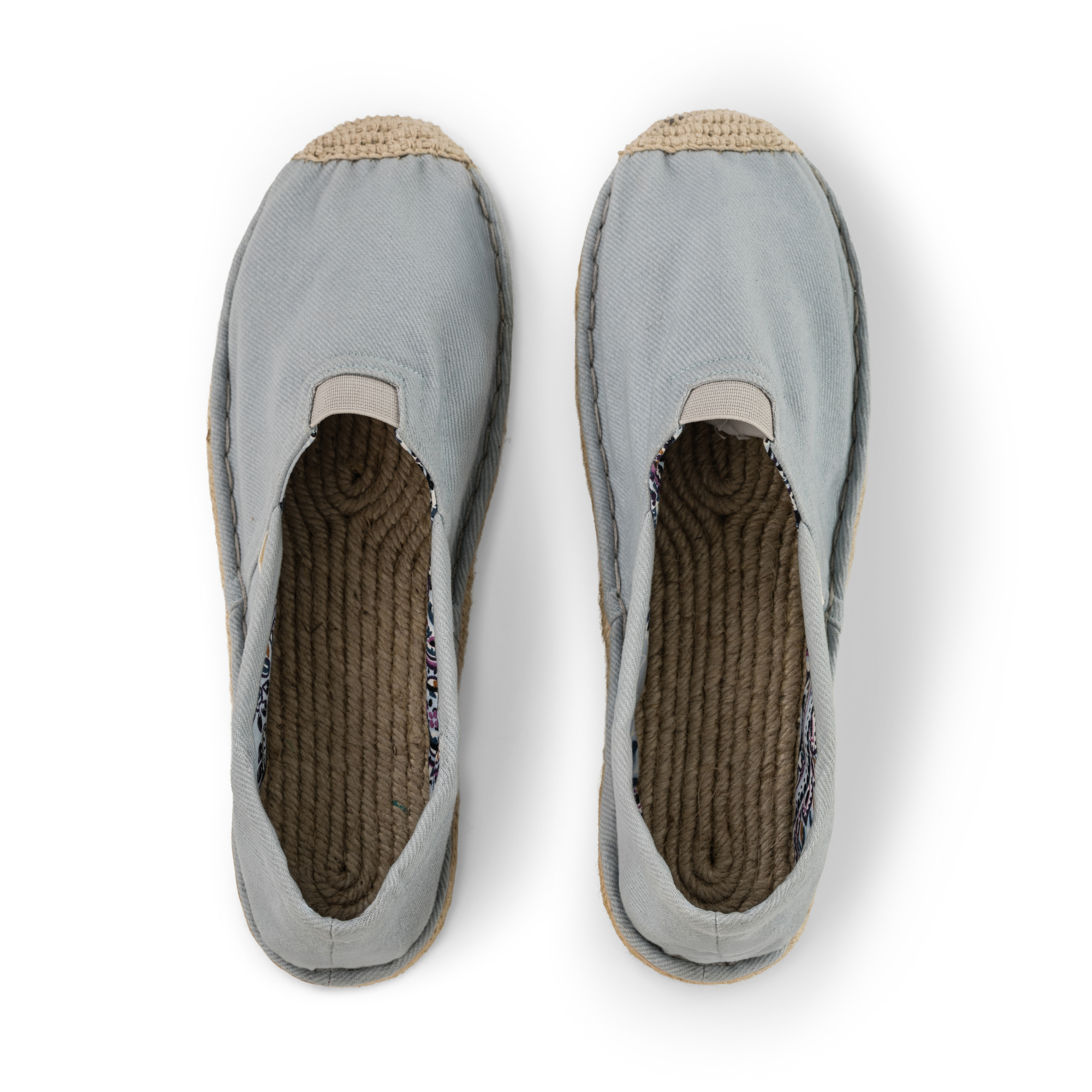 Pair of light blue espadrilles with jute sole on a white background