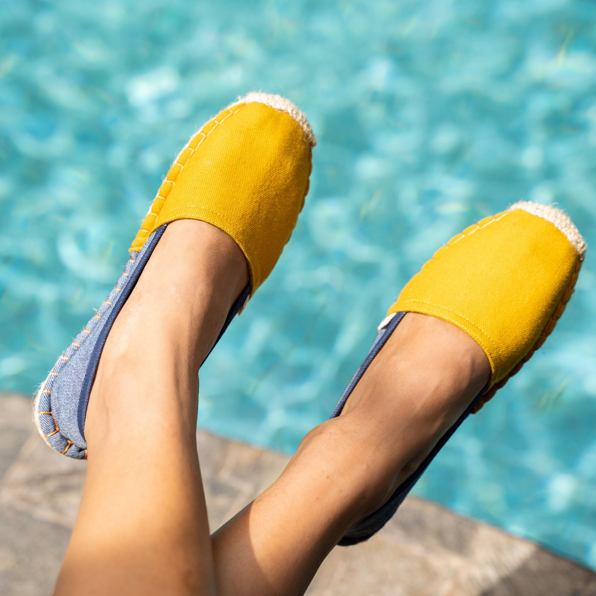 Yellow espadrilles worn by a woman with feet up poolside