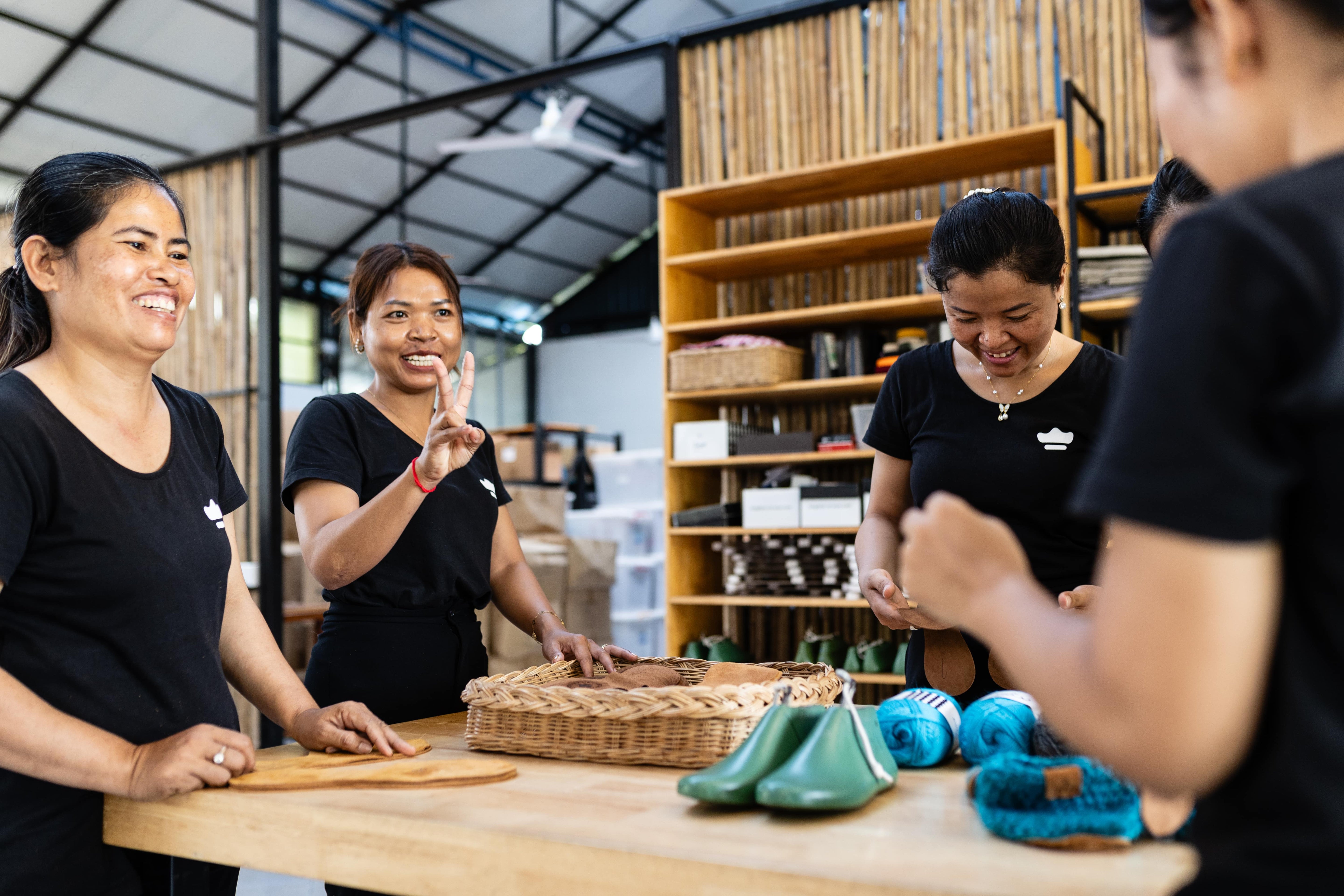 Female artisans smiling in discussion over a workbench in the workshop