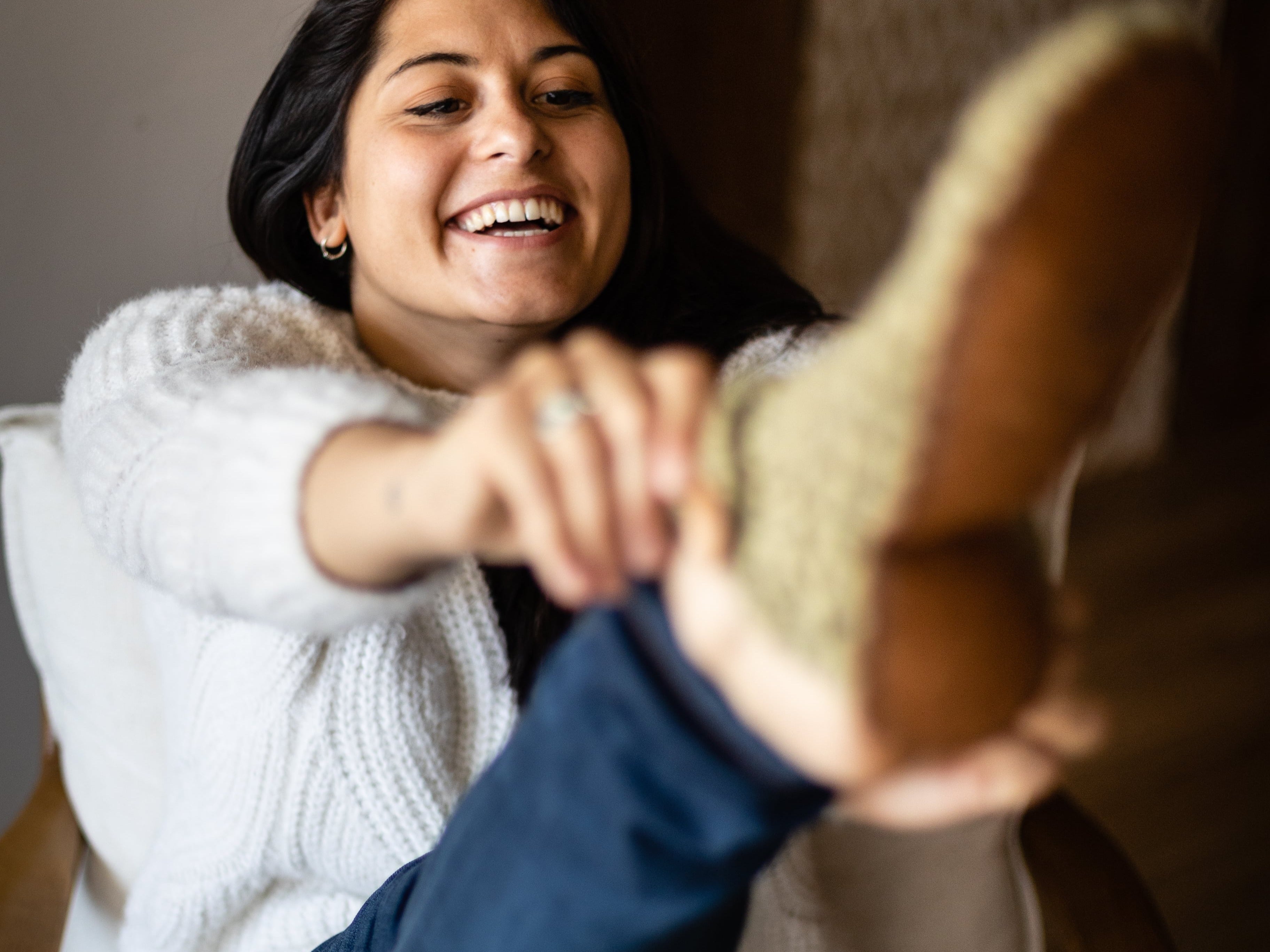 Woman smiles whilst putting on her Winter Moss Green Kingdom of Wow Bootie Slippers